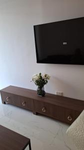 a vase of flowers sitting on a table under a television at Grand Sappfıre e4 in Larnaka