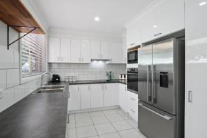 凯阿玛Kiama Beach Retreat - Big Yard & Movie Lounge的配有白色橱柜和不锈钢冰箱的厨房