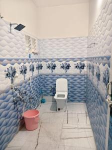 a bathroom with a toilet and blue and white tiles at Aala Stays in Tirunelveli