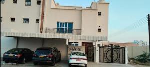 two cars parked in a parking lot in front of a building at Private Rooms And Bed Spaces Available In Sohar I18 OMR For EACH Person in Al ‘Awhī