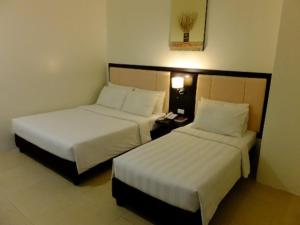ドゥマゲテにあるManhattan Suites Innのベッド2台、電話が備わるホテルルームです。