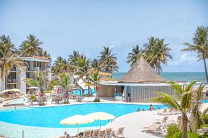 a resort swimming pool with chairs and the ocean at Kombo Oasis in Serekunda +37 photos