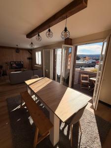 Una mesa de comedor de madera en una sala de estar con vistas. en Appartement chaleureux familial, en Saint-Laurent-en-Grandvaux