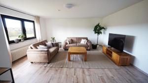 een woonkamer met twee banken en een tv bij Apartment am Golfplatz in Mackenbach in Mackenbach