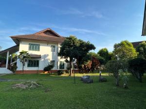a house with a yard with grass and trees at Teak Garden Resort, Chiang Rai in Chiang Rai