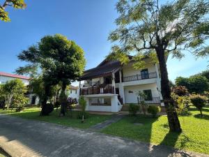 a white house with trees in front of it at Teak Garden Resort, Chiang Rai in Chiang Rai