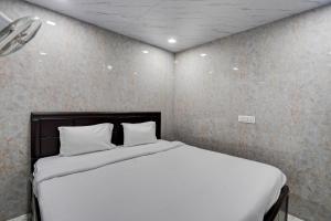 Hotel O POP A Happy Hours Plaza في نيودلهي: سرير بشرشف ووسائد بيضاء في الغرفة
