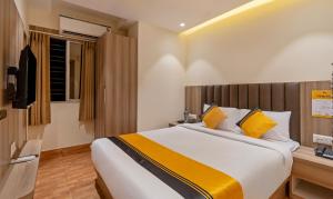 a bedroom with a large bed with yellow pillows at Itsy Hotels White Castle in Kolkata +26 photos