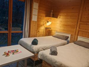 una camera con due letti, un tavolo e una lampada di Studio en Bois avec jardin clos a Bullion