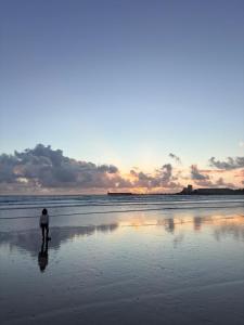 una persona parada en la playa al atardecer en Premium Ocean View Studio, Balcony & Pool, en Les Sables-dʼOlonne