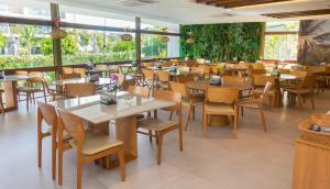 a restaurant with wooden tables and chairs and windows at Mana Beach Experience Muro Alto C219 in Porto De Galinhas