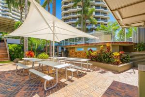 eine Gruppe von Tischen und Stühlen mit einem Sonnenschirm in der Unterkunft Serenity by the Sea in Gold Coast