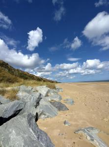 ein Strand mit Felsen im Sand und blauem Himmel in der Unterkunft Antonia's Place 337 California Sands in Scratby + 4 Fotos