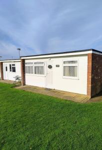 ein großes weißes Gebäude mit einem Rasenplatz in der Unterkunft Antonia's Place 337 California Sands in Scratby