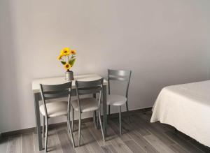 een tafel met vier stoelen en een vaas met bloemen erop bij Estudio cerca de la playa y del centro de conil in Conil de la Frontera