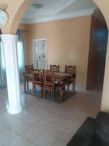 Jeng's paradaise green house في Sukuta: غرفة طعام مع طاولة وكراسي خشبية +صورتان