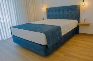 a bedroom with a large bed with a blue headboard at Coração de Viana AL in Viana do Castelo