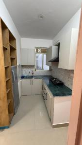 a kitchen with white cabinets and a green counter top at Krishna Heights in Karnal