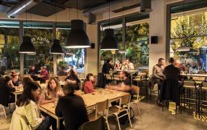 Charming Acropolis Flat with stunning Roof Terrace في أثينا: مجموعة من الأشخاص يجلسون على الطاولات في مطعم