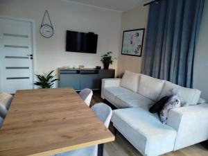 a living room with a white couch and a wooden table at Apartament na Letniej in Kłodzko