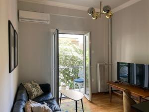 Charming Acropolis Flat with stunning Roof Terrace في أثينا: غرفة معيشة مع أريكة وباب زجاجي منزلق