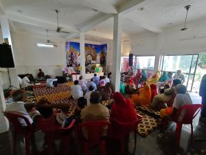 a group of people sitting in chairs in a room at Pawansut Dham in Naimishāranya