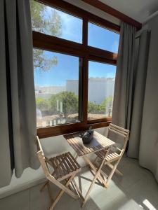 2 Stühle und ein Tisch vor einem Fenster in der Unterkunft Eftyhia's Cozy apartment Patmos in Skala