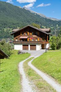 a house on a hill with a dirt road in front at Chalet Studen in Grindelwald