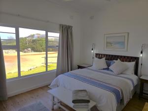 una camera da letto con un letto e una grande finestra di The Kei Mouth Guest Lodge Collection a Kei Mouth