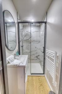 een badkamer met douche, wastafel en spiegel bij La porte de Mars - Air conditioning in Reims +27 foto's