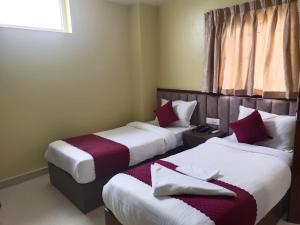 2 łóżka w pokoju hotelowym z białymi i czerwonymi poduszkami w obiekcie Merigold Hotel & Spa Palace PVT LTD w mieście Bākhri Kharka