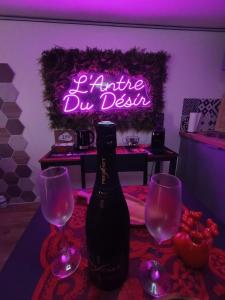 a bottle of wine and two wine glasses with a neon sign at L'Antre Du Désir in Wierre-Effroy