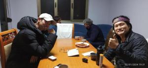 Eine Gruppe von Menschen, die an einem Tisch sitzen und Essen essen. in der Unterkunft Royal 2 Hostel Opposite NALU BAR in Tirana