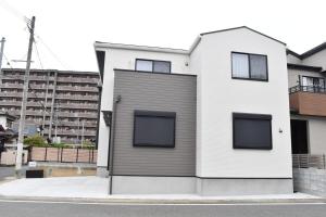 una casa blanca con ventanas negras en una calle en 福の荘 空港3号棟, en Wada