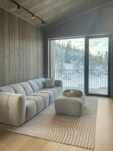 sala de estar con sofá grande y ventana grande en Architect Designed Mountain Cabin At Kvitfjell, en Favang