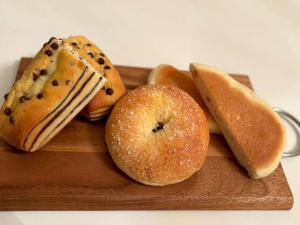 a wooden cutting board with pastries and donuts on it at Grampus Inn Osaka Namba in Osaka