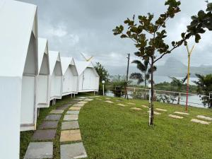 a walkway next to a white building with a tree at Pawna Lake Camping Bramhnoli in Lonavala