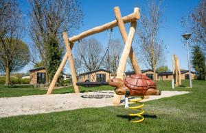 Un parque infantil con una tortuga y un columpio. en Cozy escape near Den Bosch - 4 PS chalet met veel privacy en rust!, en Lith