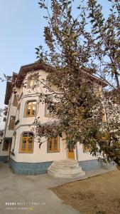a large white building with yellow windows and a tree at The Vintage Kashmir Homestay in Srinagar