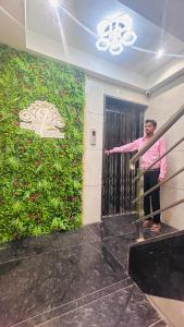 a man standing at the door of a room with a flower wall at Hotel Signature in Thane