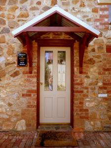 eine Eingangstür eines Backsteingebäudes mit einer weißen Tür in der Unterkunft Barossa Barn Bed and Breakfast in Angaston