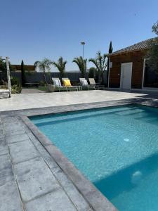 een zwembad met twee stoelen en een huis bij צמרת נופש in Rewaya +7 foto's