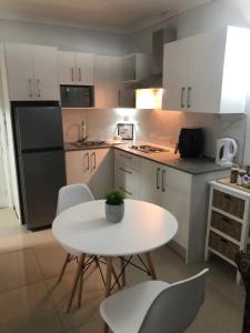 a white kitchen with a white table and chairs at Relaxing Hideaway in Strand