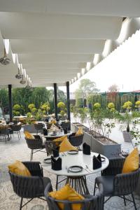 a patio with tables and chairs with yellow pillows at JBM resort & hotel in Jāmb