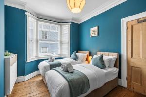 two beds in a room with blue walls at The Quirk & Timber Retreat with Free parking in Brighton & Hove