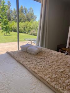 un letto con cuscini in una stanza con una finestra di Alojamiento en Paine 