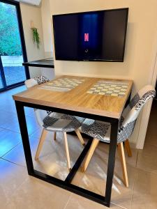 a wooden table with two chairs and a television at La maison des Oiseaux in Trans-en-Provence