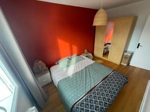 Un dormitorio con una cama y una pared roja. en Grand T2 lumineux et cosy - 1min Termes Marlioz, en Aix-les-Bains