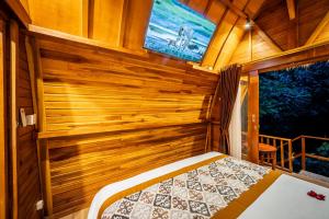 a bedroom with a bed in a wooden room at Oemah Ubud - Waterfall in Gianyar