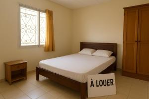 een slaapkamer met een bed, een raam en een lade bij Chez Amina in Mbour